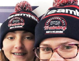 a close up of two women wearing their gym's branded beanies